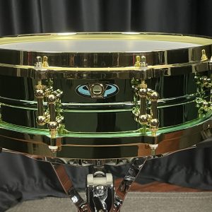 Ludwig Carl Palmer three point seven by fourteen inch Brass Piccolo Venus. shiny greenish anodised shell finish with brass colored tube lugs and die-cast hoops badge is elongated oval with keystone emblem in center at air vent