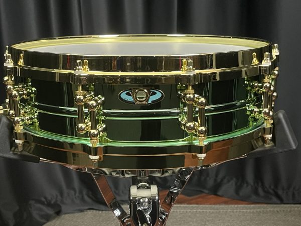 Ludwig Carl Palmer three point seven by fourteen inch Brass Piccolo Venus. shiny greenish anodised shell finish with brass colored tube lugs and die-cast hoops badge is elongated oval with keystone emblem in center at air vent